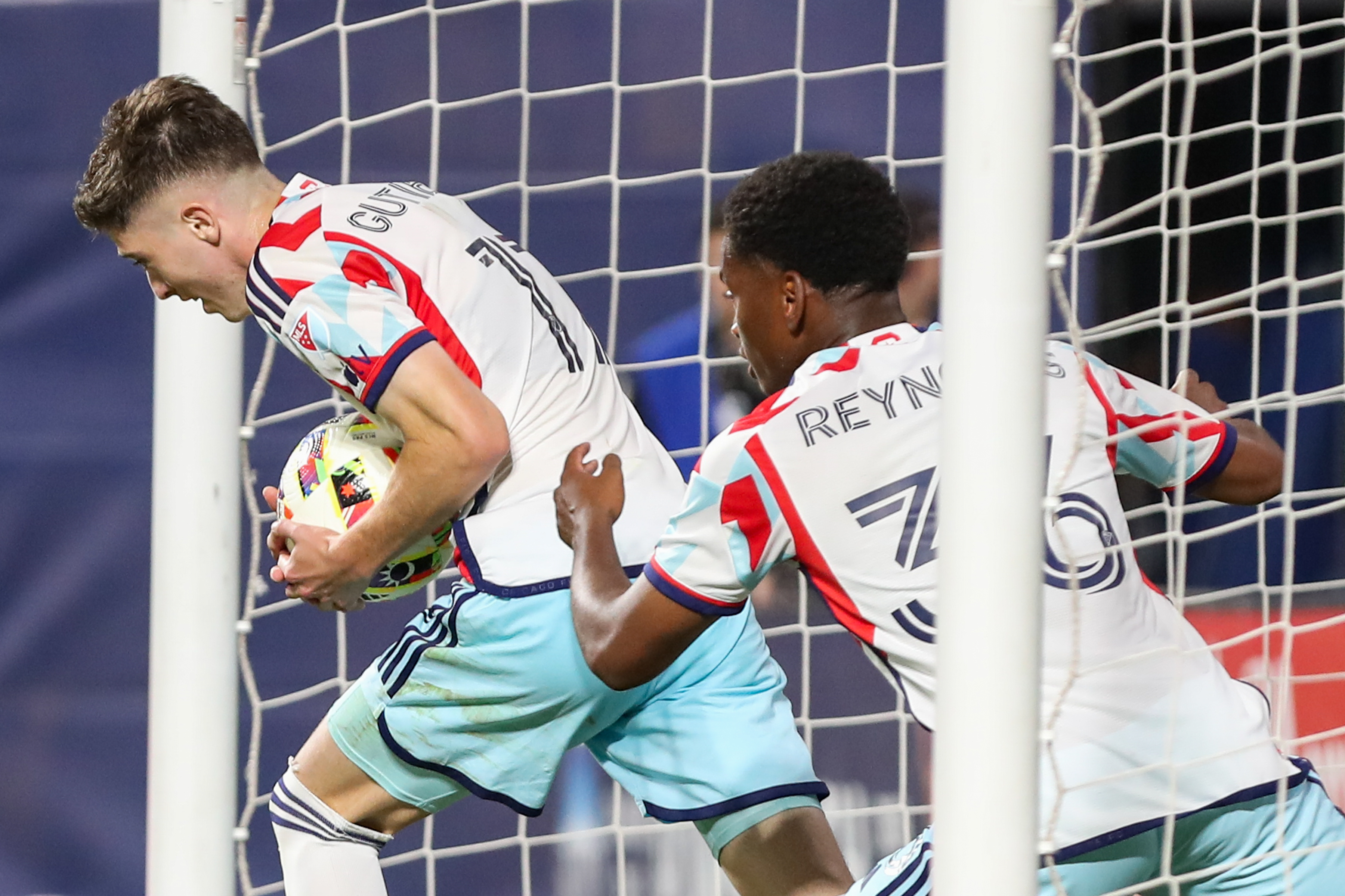 Chicago Fire soccer player Brian Gutierrez takes the ball out of the net after scoring a goal as Fire player Justin Reynolds chases him to celebrate with him