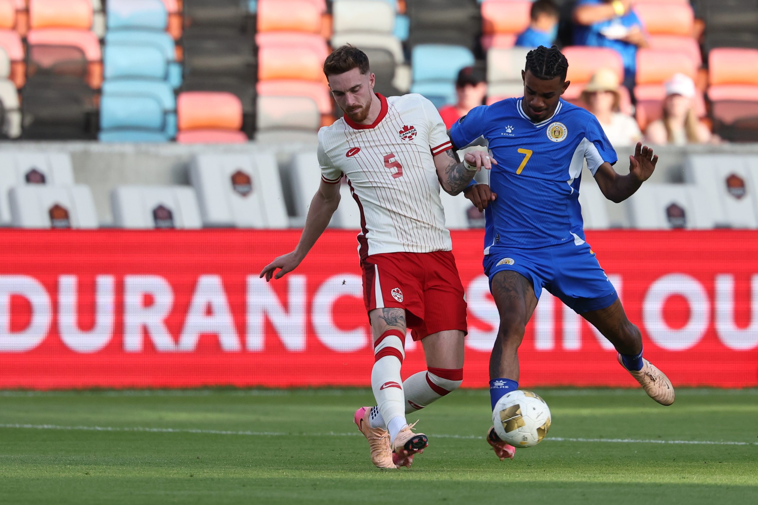 Jun 21, 2025; Houston, Texas, USA; Canada defender Joel Waterman (5) battles for the ball against Curacao midfielder Juninho Bacuna (7) during the second half during a group stage match of the 2025 Gold Cup at Shell Energy Stadium. Mandatory Credit: Troy Taormina-Imagn Images